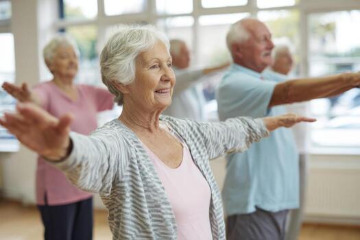 A group of seniors engages in a lively exercise class at a local community center. They practice gentle movements, stretching arms and enjoying the social interaction photo