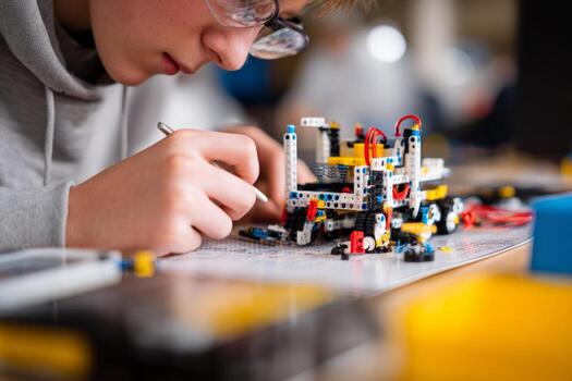 A boy concentrates on building a robotic model using colorful building blocks and wires in a classroom during a STEM workshop focusing on hands-on education photo
