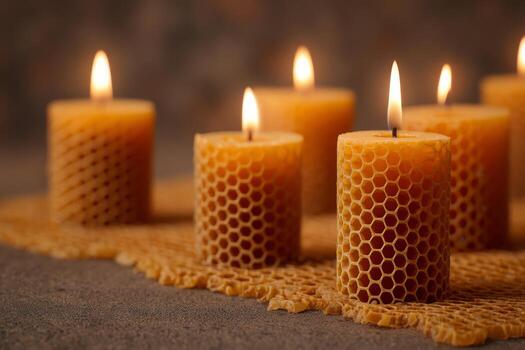 A collection of honeycomb candles emits a warm glow, arranged artfully on a textured surface. The candles flicker softly, creating a tranquil and inviting ambiance photo