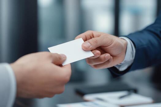 Two individuals are exchanging business cards in a professional environment. The focus is on their hands, highlighting the significance of networking and building connections photo