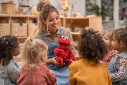 A teacher shows a red puppet to a group of excited children in a bright classroom. The kids are sitting attentively, enjoying the interactive session photo