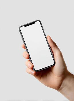Hand holding a smartphone with a blank, bright white screen. Diagonal angle, light background photo