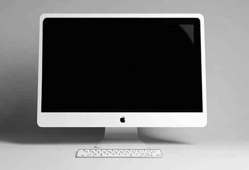 A white, sleek desktop computer and keyboard sit on a white surface against a gray backdrop photo