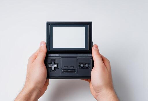 Person's hands hold an open, black, handheld gaming device with a blank screen on a white background photo