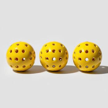 Three yellow, perforated spheres on a white surface, each casting a shadow photo