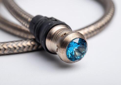 Close-up of a silver cable with a blue crystal gem at the end, on white background photo