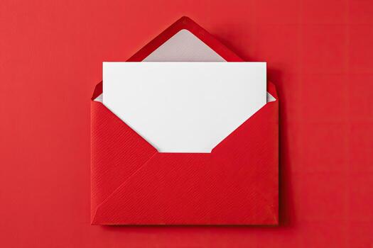 A bright red envelope, partially open, holding a blank white card on a solid red background photo