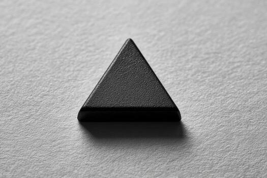 Close-up of a matte black triangle on a light gray surface photo