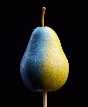 A pear, split diagonally, with a gradient blue and yellow color scheme, on a black backdrop photo