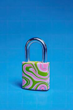 A close-up of a patterned padlock on a blue grid. The colors are pink, green, and white photo