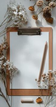 Empty clipboard with dried flowers photo