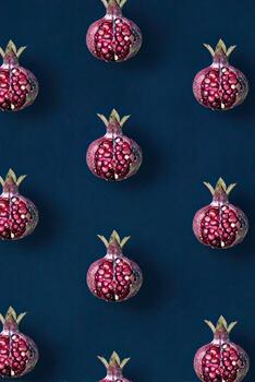 Repeating pattern of halved pomegranates with vibrant red seeds against a dark blue backdrop photo