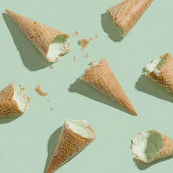 Overhead shot of partially eaten ice cream cones on a light green surface, casting shadows photo
