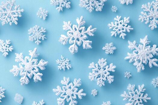 Overhead shot of varying sizes of white snowflakes scattered on a light blue surface photo