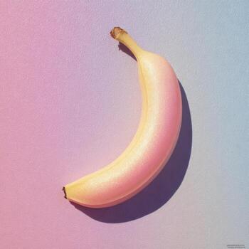 A banana glows with a gradient of pink and yellow on a pastel blue and pink backdrop photo