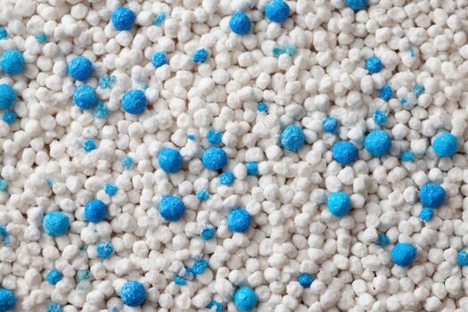 White cat litter round particles surface with small blue colored particles, top view. Granules of pet white-gray litter background. Dog litter texture backdrop with small dots. Flat lay, copy space photo