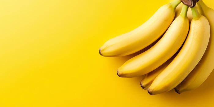 Bananas. Banana Bunch isolated on a bright yellow background. Ripe banana fruits on plain color studio backdrop. Copy Space. Tropical summer flat lay frame. Top view. Long Wide Banner photo