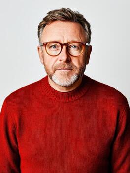 Confident Middle-aged Man with Glasses in Bright Red Sweater Against Plain Background photo