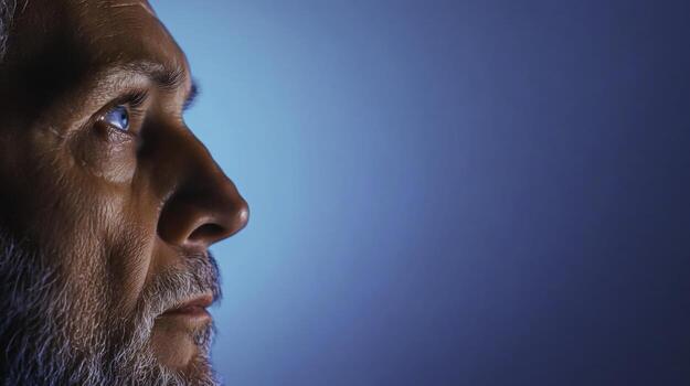 Profile of a Thoughtful Bearded Man Against a Soft Blue Background with Supple Lighting photo