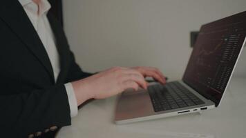 Close-up of professional trader typing on laptop computer with digital trading platform, showing crypto and stock market graphs for finance and business use video