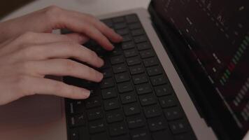 fechar-se do mãos digitando em computador portátil teclado enquanto financeiro gráficos e digital analytics preencher a tela, simbolizando moderno finança e controlo remoto o negócio soluções video