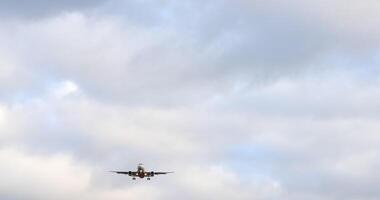 A passenger airplane with its landing gear down and lights on is approaching for landing against a background of clouds. video