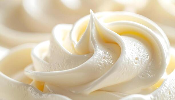 Close-up view of a swirled texture of creamy, light-colored frosting, highlighting its smooth and soft appearance. photo