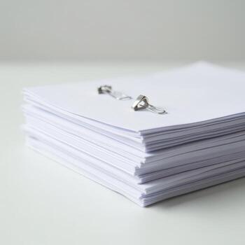 Stack of white papers clipped together with metal fasteners on white table photo