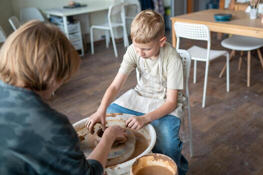 Child and instructor shap jing clay together at pottery workshop photo