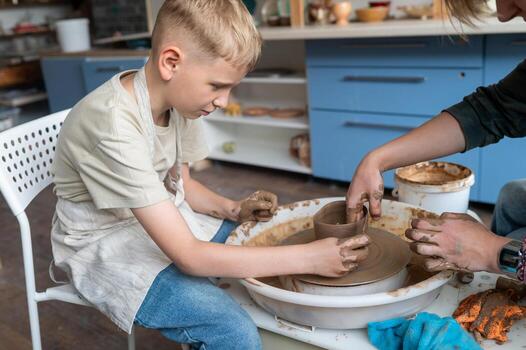 Child and instructor shaping clay together at pottery workshop k photo