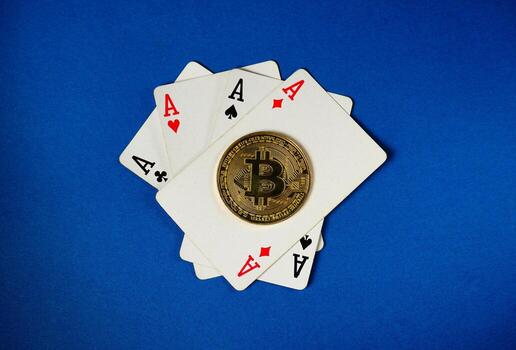 Several playing cards showing aces are arranged with a shiny bitcoin coin in the middle, set on a vibrant blue background, capturing the intersection of gaming and digital currency photo