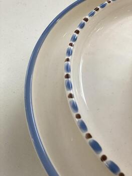 de cerca de cerámico plato borde con azul y marrón punto modelo en blanco superficie, resumen antecedentes foto
