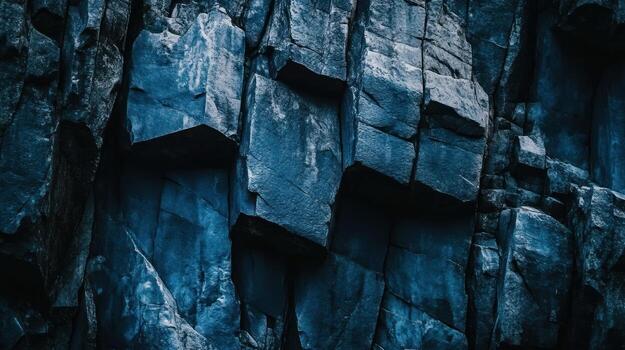 Close-up of a dark blue, rugged rock face with sharp, irregular angular formations and deep crevices, exhibiting a textured, natural stone surface photo