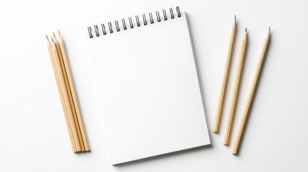 Blank notebook and colored pencils on a white surface photo