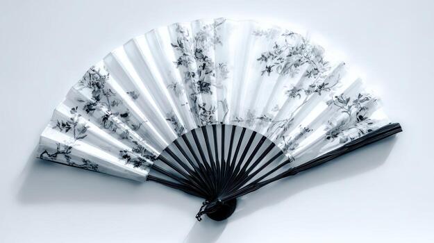 Open, decorated fan with a black frame, displayed on a light surface photo