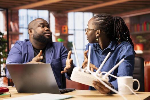 Irritated black couple getting angry over Wi Fi signal loss during remote work, trying to reboot the modem to fix the issues or find a solution. Troubleshooting or debugging the wireless router. photo