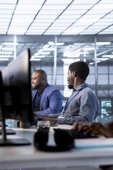 Team of admin talking and having fun in server hub while monitoring data center energy consumption across components, making sure sensors are functioning optimally, doing routine disk checks photo