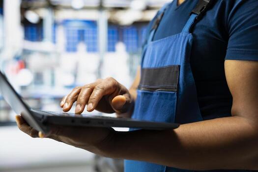 Male engineer works on solar energy software settings in high tech factory, optimizing the production process. Optimal system configuration with digital tools and industrial robotics. Close up. photo