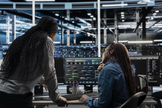 Technicians working together programming in server farm housing infrastructure storing datasets. IT experts collaborating, running code on PC to repair data center racks doing computational operations photo