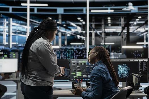 Data center engineers talking, doing brainstorming, using artificial intelligence visualization tools to identify errors. Server hub coworkers working together, looking at insights photo