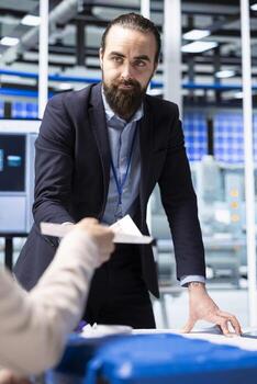 Factory management executives looking over paperwork documents, discussing solar panel automation strategies. Team analyzing documentation files data to enhance sustainable manufacturing processes photo