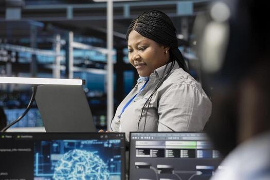 Smiling technician in data center uses AI technology for machine learning workloads. Happy server hub facility worker using artificial intelligence to perform demanding computing tasks photo