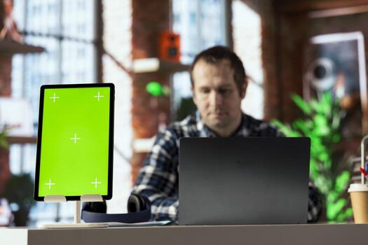 Focus on green screen tablet used by employee in blurry background, editing documents, typing text. Close up of mockup device used by remote worker managing digital paperwork within file directories photo