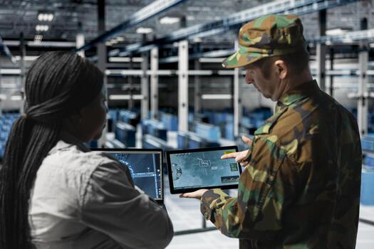 Military server hub personnel analyzing surveillance data together in secure command center. Commander in data center verifying intel accuracy with IT specialist reviewing live tactical feed on screen photo