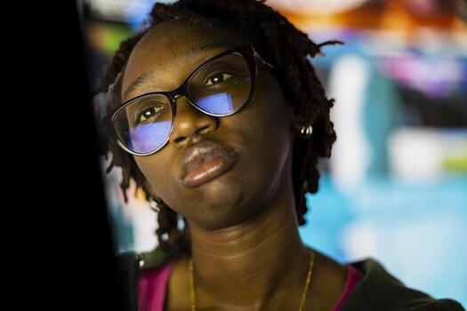 Close up of woman looking at laptop screen with dull expression, showing boredom and lack of motivation while browsing internet. African american person looking uninterested at notebook display photo