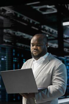 Server hub developer using laptop to fix network issues affecting storage arrays, doing backups. Programmer in data center runs system diagnostic tests, scanning hardware logs for faults photo