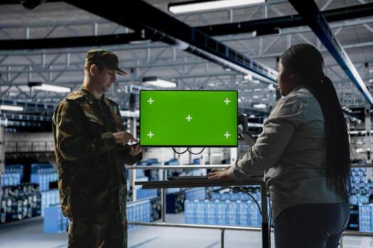 IT specialist briefing commander in army server hub using isolated screen monitor. Military officer in data center and engineer monitoring warfare drone telemetry using chroma key display photo