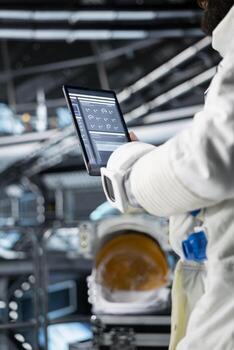 Close up of astronaut reviewing spacecraft diagnostics on tablet to ensure safe operation during space travel. Crew member monitors system stability while preparing for next phase of cosmic journey photo