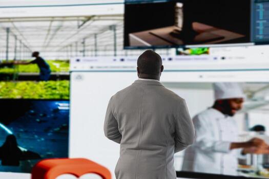 Man facing digital wall, benefiting from endless entertainment selection. Viewer enjoying access to various streaming options, looking at screens displaying movies and TV shows clips photo