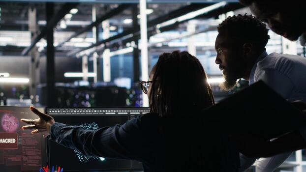 Cybersecurity team in data center responds to security breach, trying to prevent unauthorized access. Workers rushing to secure servers and protect sensitive information during cyberattack, camera B photo
